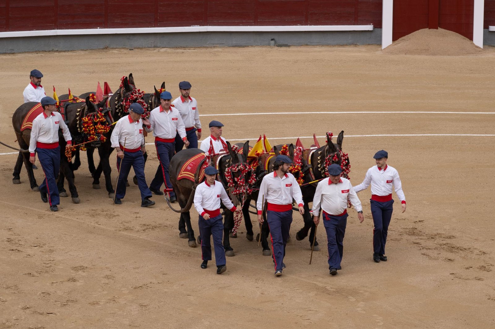 Men lead decorated horses in a festive bullring procession, representing Mexican culture and tradition in Madrid, Spain