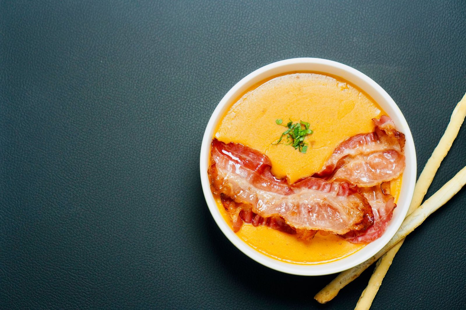 Delicious bowl of creamy soup garnished with crispy fried bacon, perfect for comfort food lovers