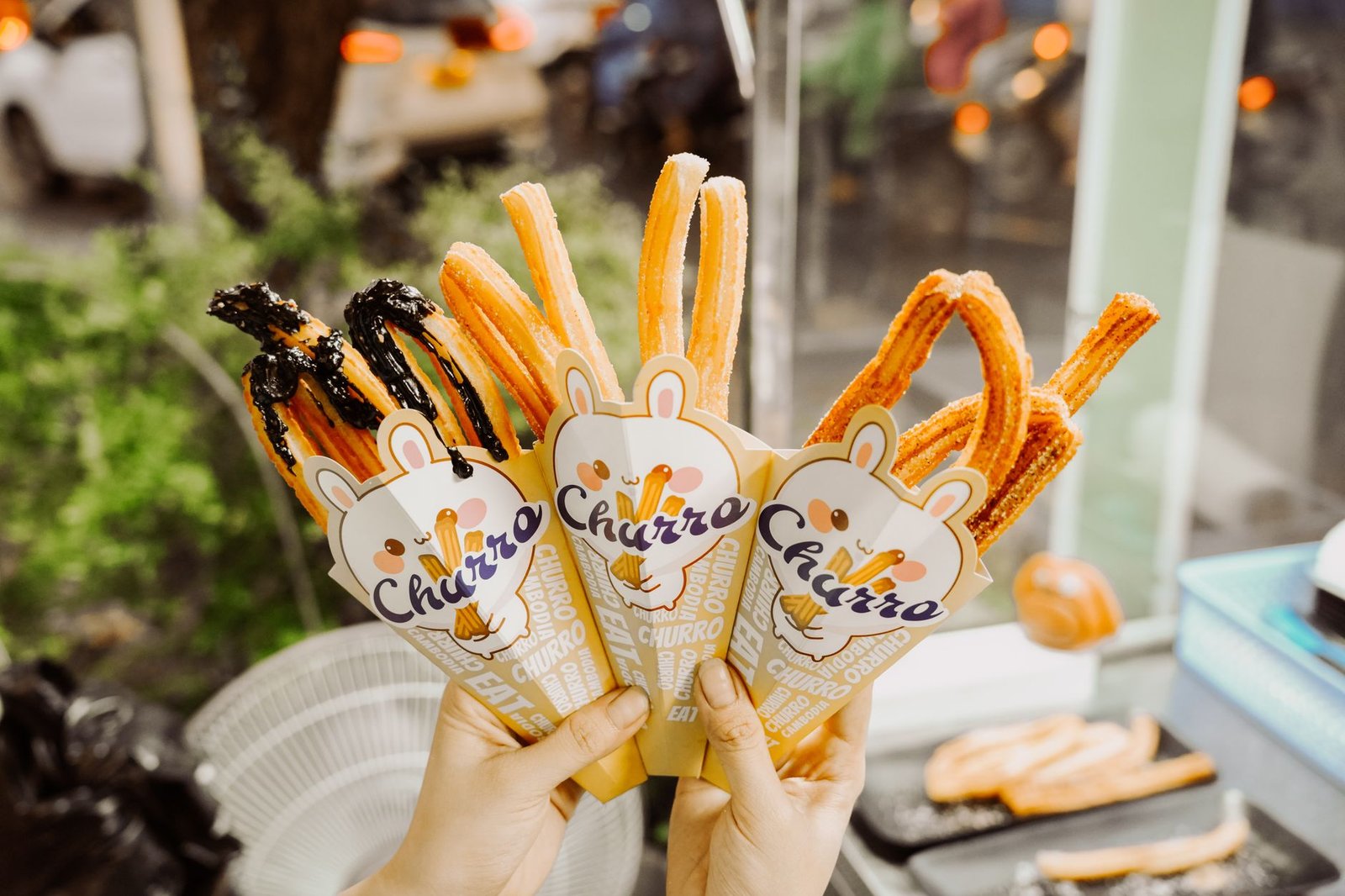 Close-up of gourmet churros in cones being held outdoors. Perfect sweet street snack