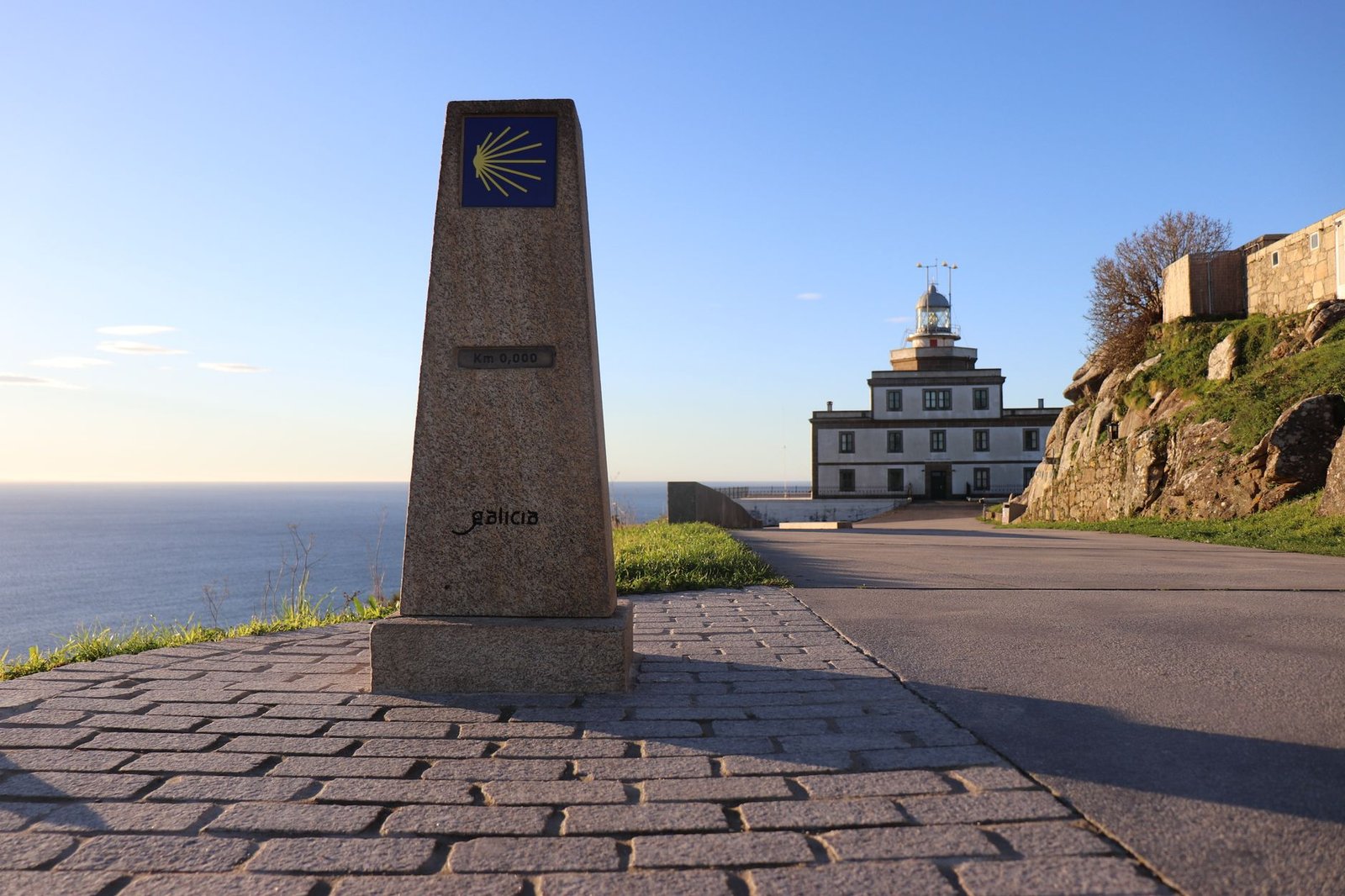 Cabo Fisterra lighthouse under clear blue sky in Galicia, Spain with kilometer zero landmark