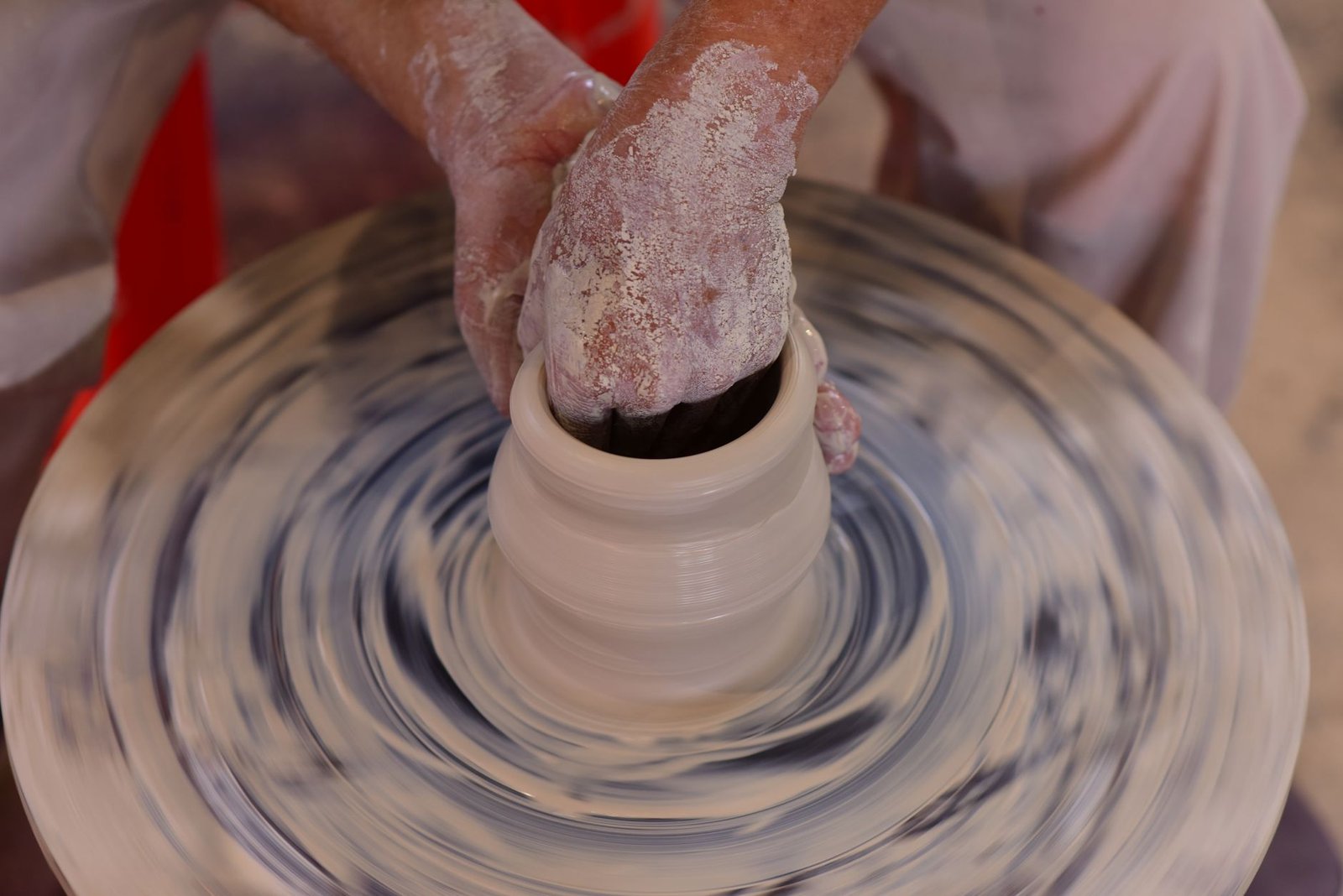 Hands expertly shaping clay on a pottery wheel, illustrating the art of ceramic creation