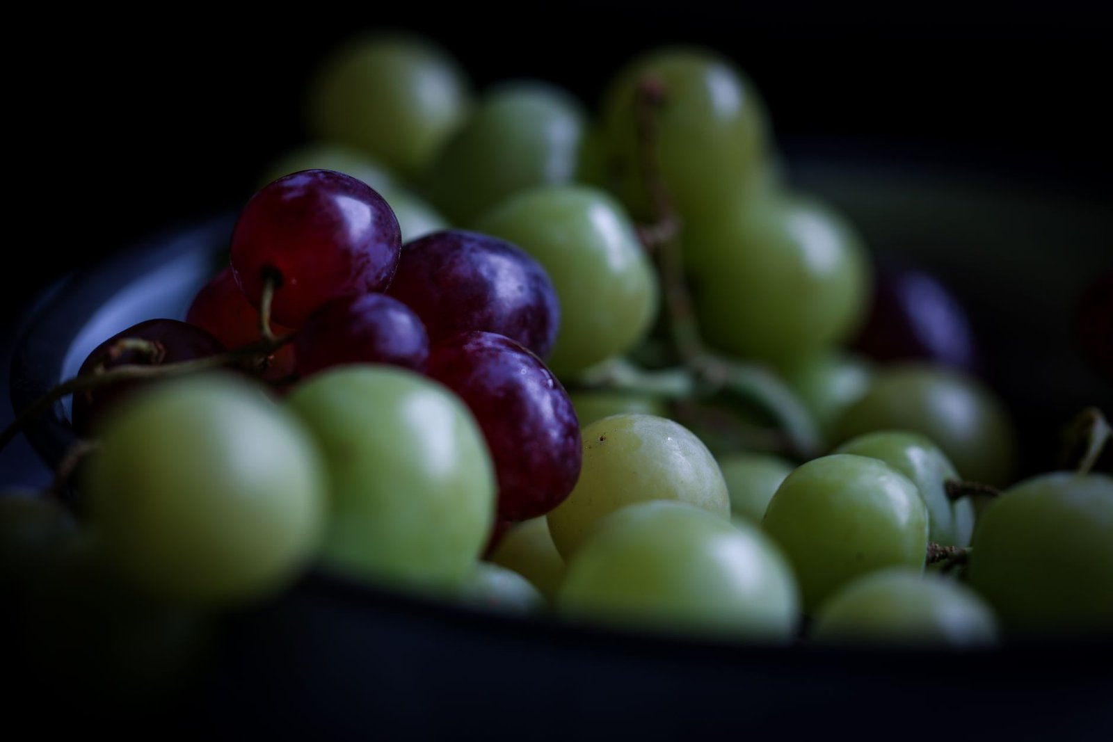 A vivid image of ripe red and green grapes in a bowl, showcasing their natural textures