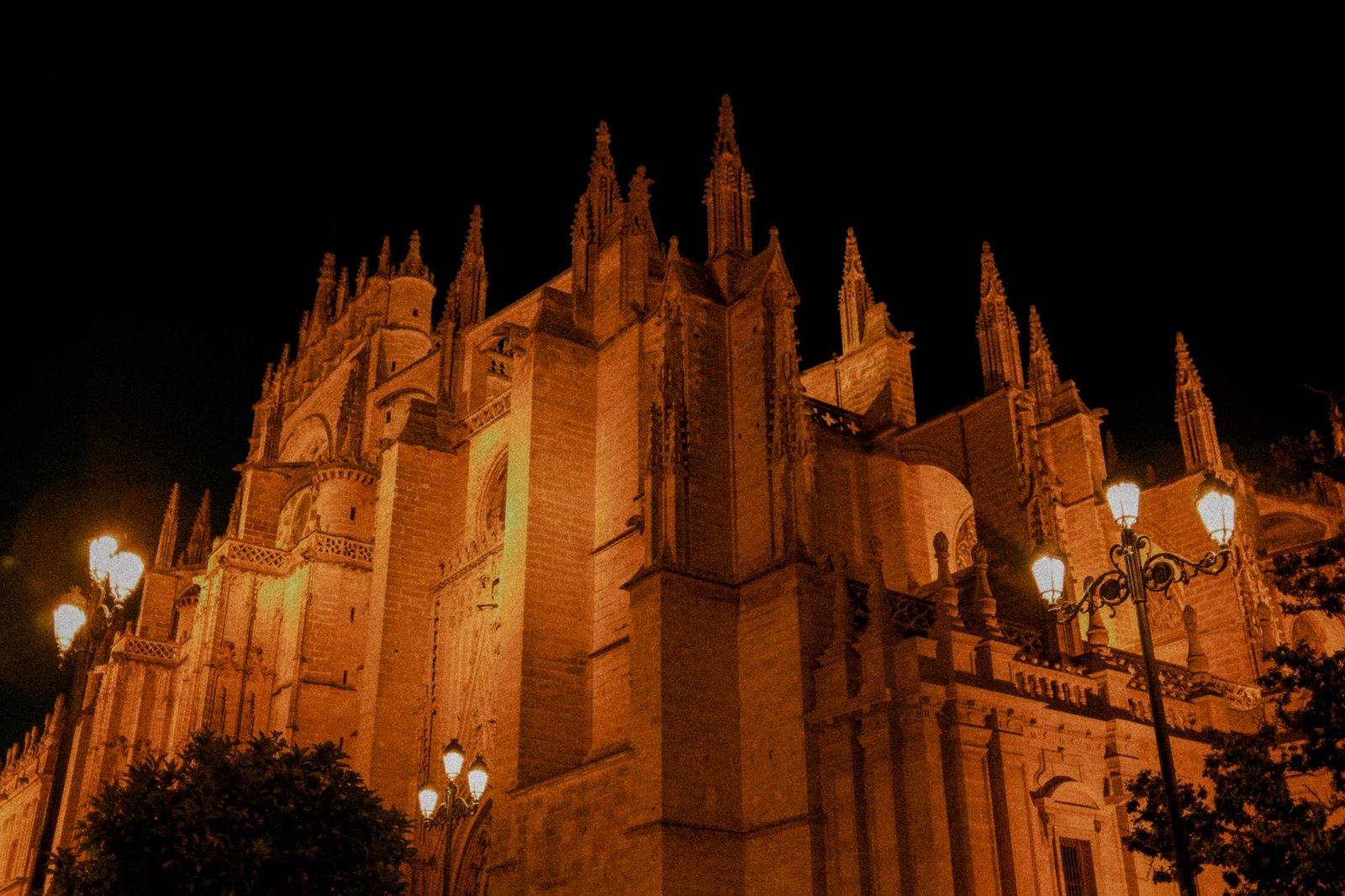 Night view of the Seville Cathedral, showcasing Gothic architecture under street lighting