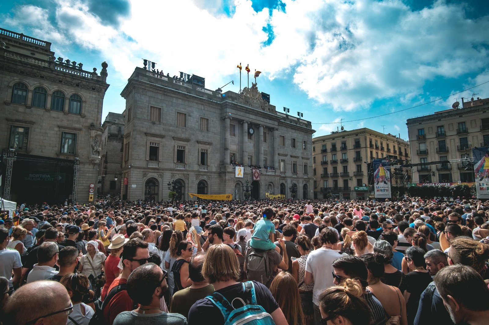 A lively gathering in a historic plaza in Barcelona, showcasing urban life under a bright sky