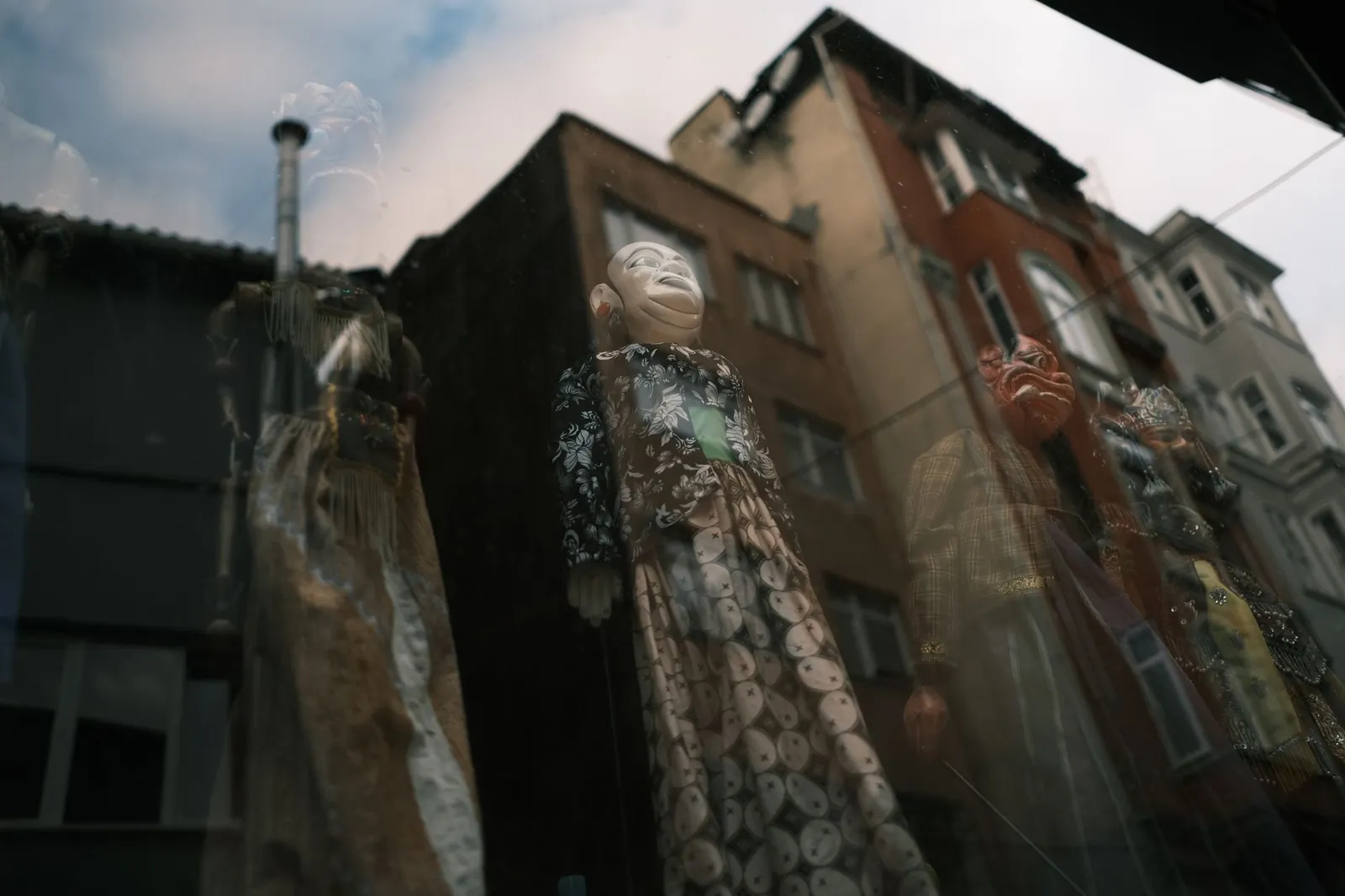 Artistic reflection of puppets through a window with urban buildings in the background