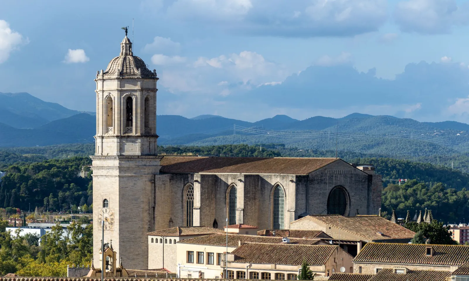 A beautiful view of Girona Cathedral against a mountain backdrop and clear blue skies