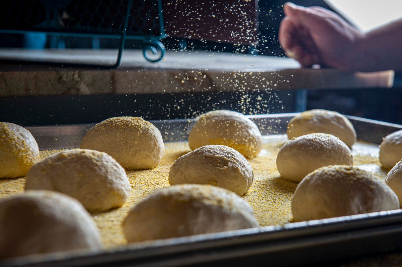 Close-up of dough balls in a bakery setting, ready for baking with a sprinkle of flour