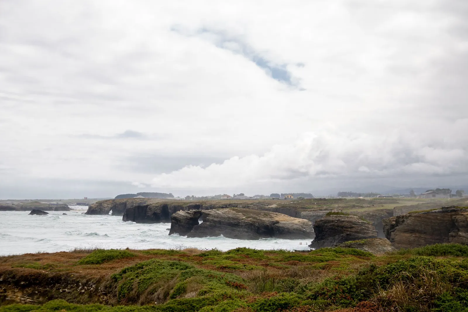Explore the coastal cliffs of Lugo, Spain with greenery and crashing waves