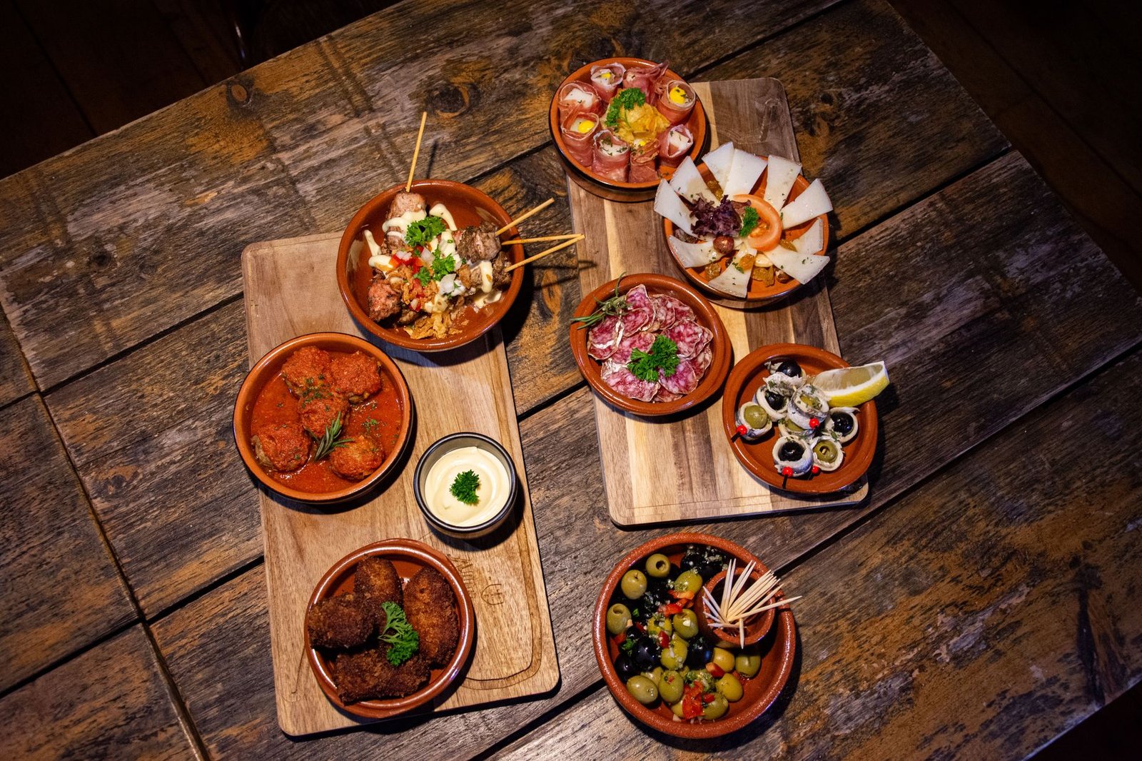 An inviting flat lay of diverse gourmet tapas on a wooden table, perfect for a rustic dining experience