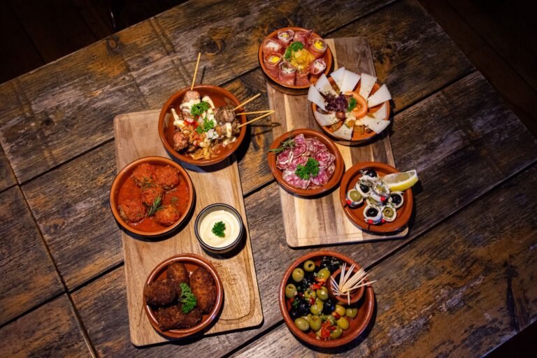 An inviting flat lay of diverse gourmet tapas on a wooden table, perfect for a rustic dining experience