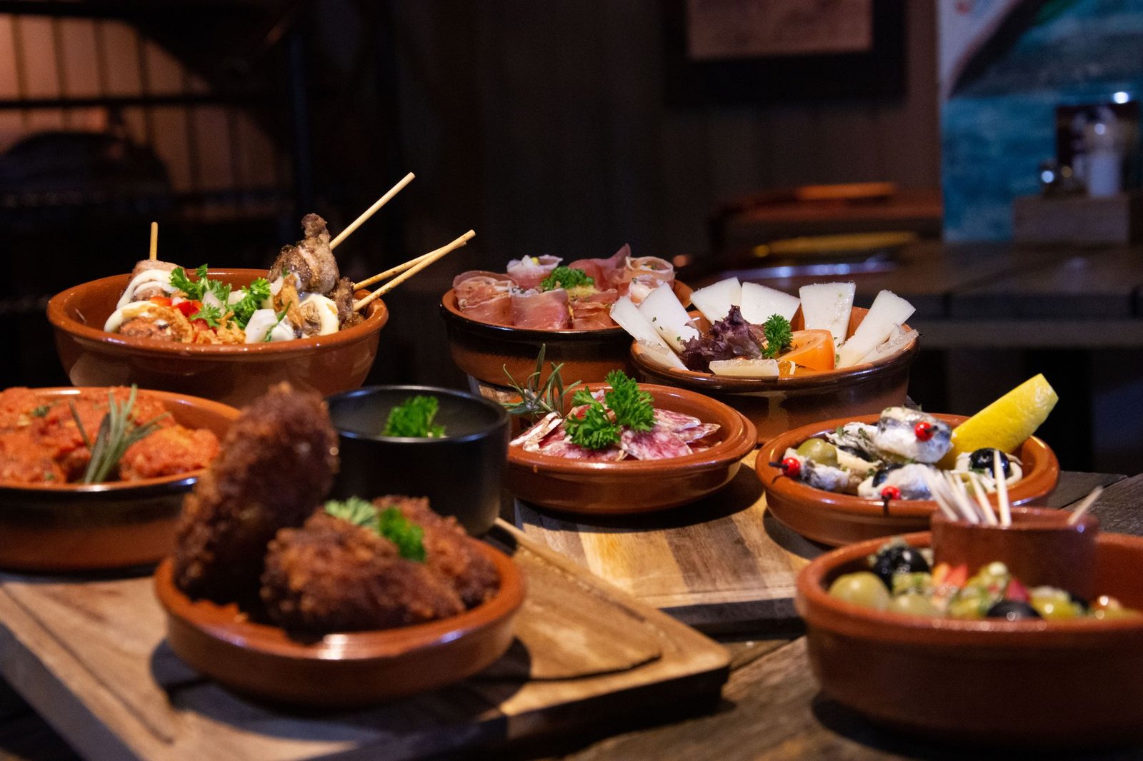 An inviting spread of various tapas dishes elegantly arranged in a cozy indoor restaurant ambiance