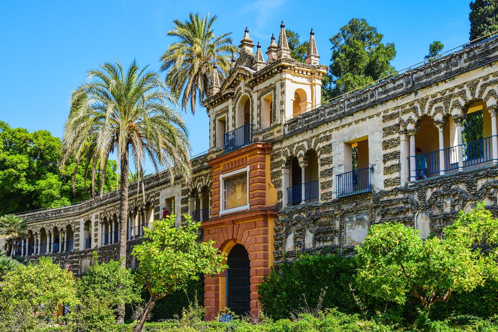 Discover the Alcazar Palace with gardens, palm trees, and historic architecture in Seville, Spain