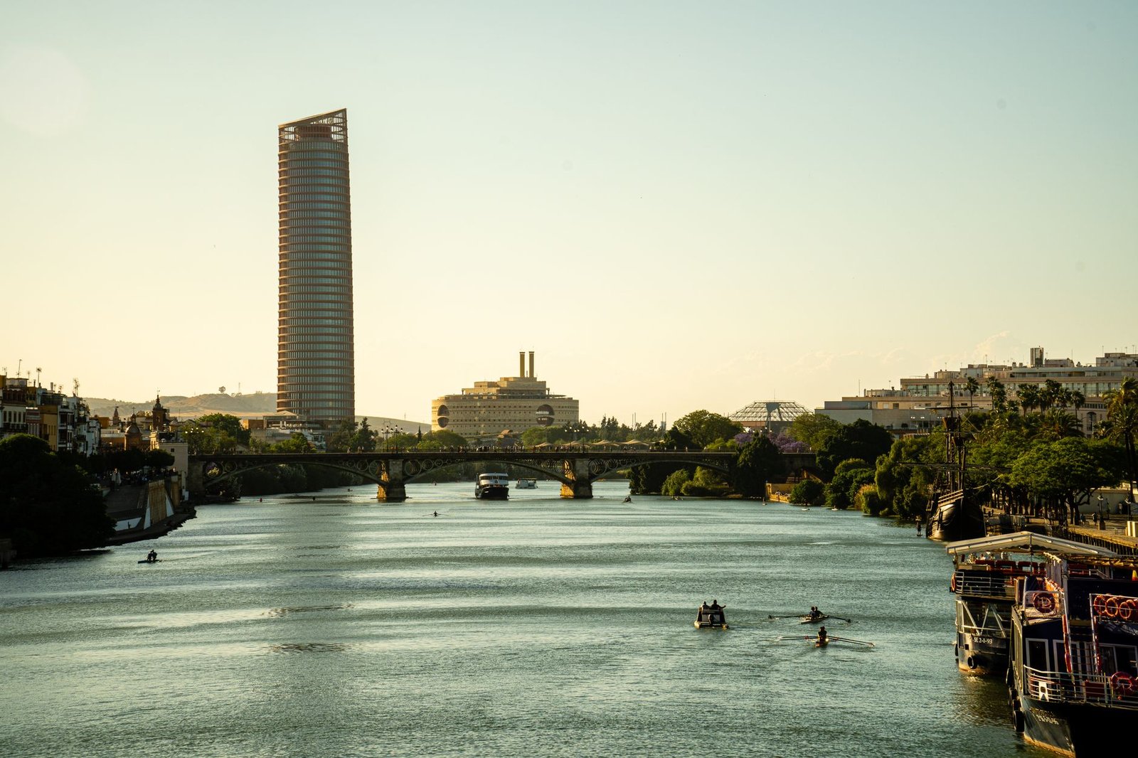 Tranquil view of Seville's river, modern bridges, and city skyline at sunset
