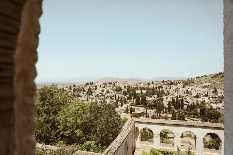 Panoramic view of Granada cityscape framed by historic architecture under a summer sky