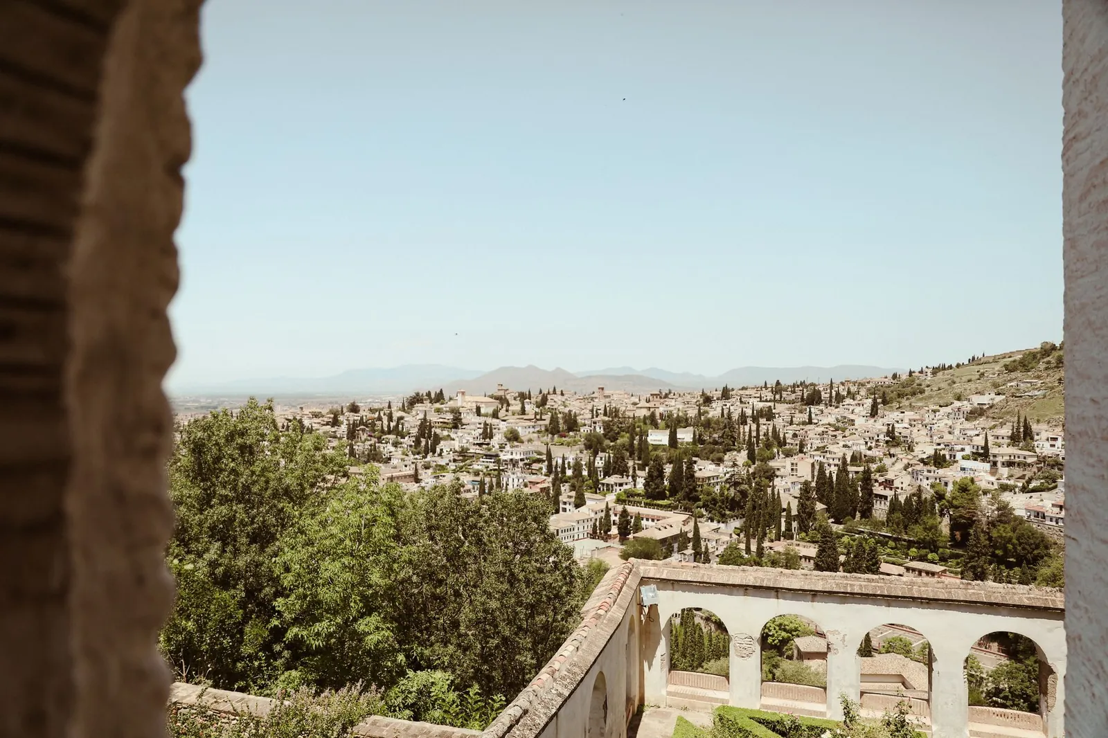 Panoramic view of Granada cityscape framed by historic architecture under a summer sky