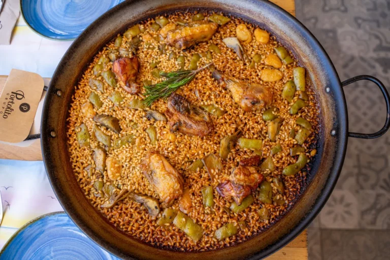 Authentic Valencia paella in a pan with chicken, vegetables, and rosemary. Top view