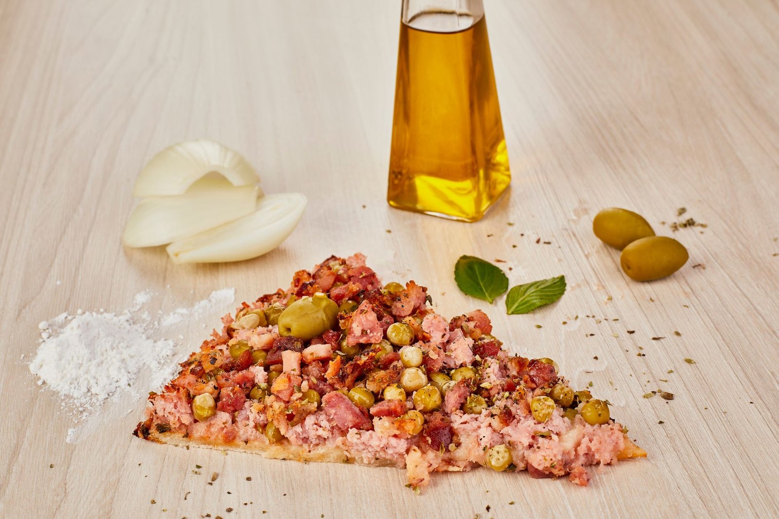 Close-up of Italian pizza slice with olives, onions, and oil on a wooden surface