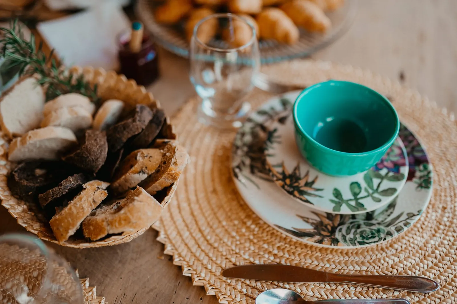 Cozy breakfast setup with various breads and ceramic tableware on a woven placemat
