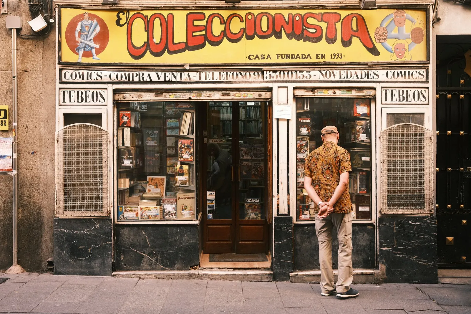 A man window shopping outside a vintage comic store in Madrid, Spain