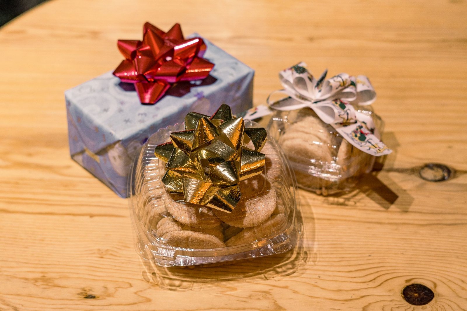 Decorative gift box and cookies wrapped with festive bows on a wooden table, ideal for holiday themes