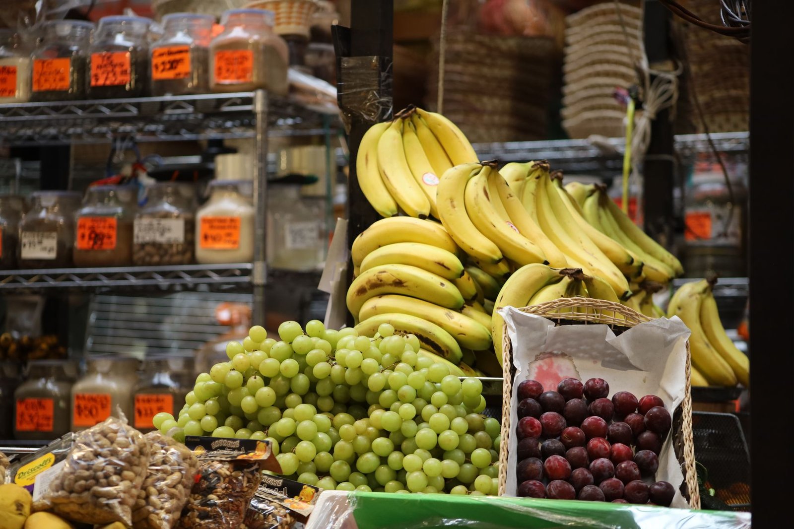 A assortment of bananas, grapes, and plums at a market stand