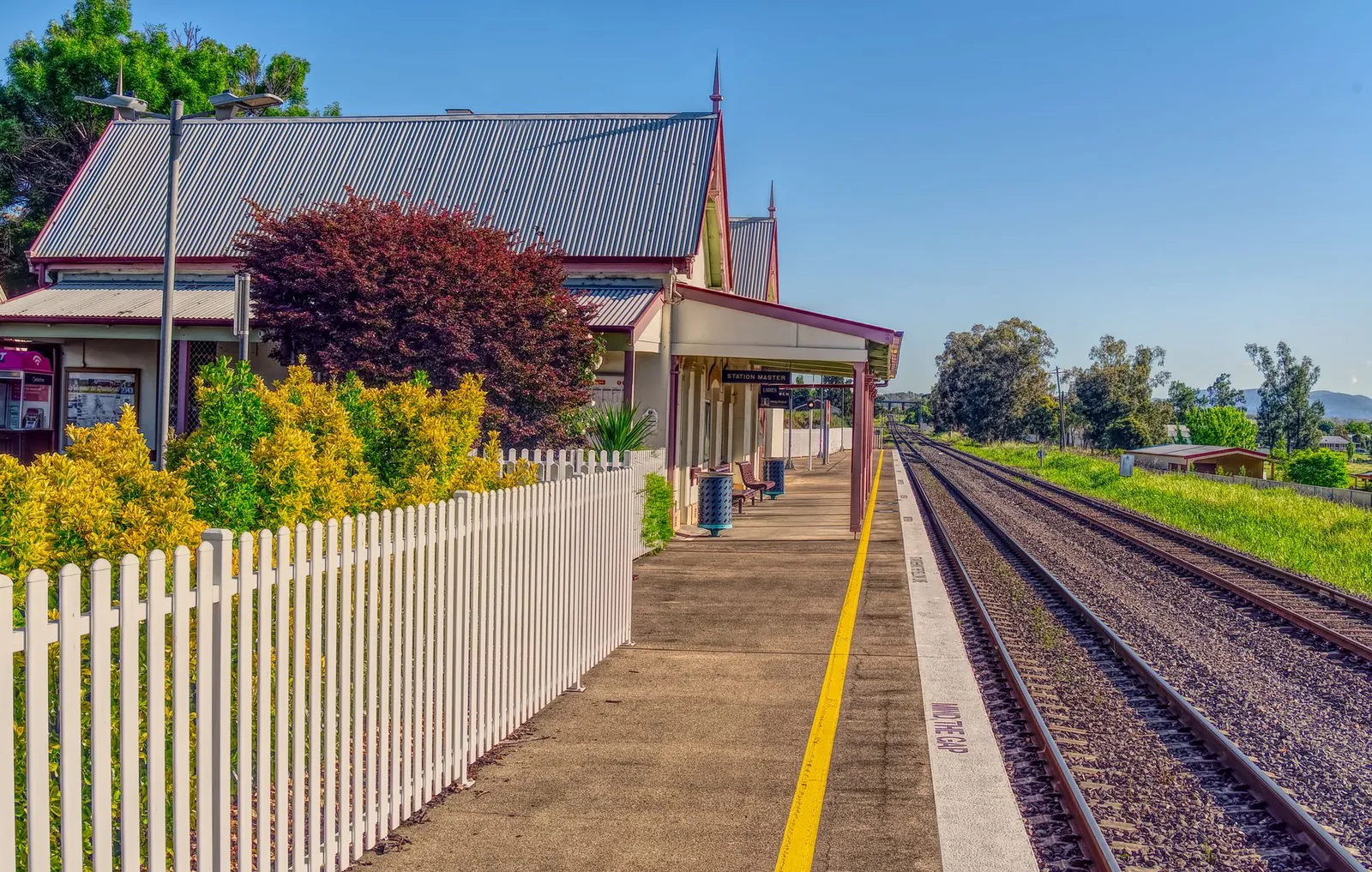 rural train station with tracks leading into the distance on a sunny day