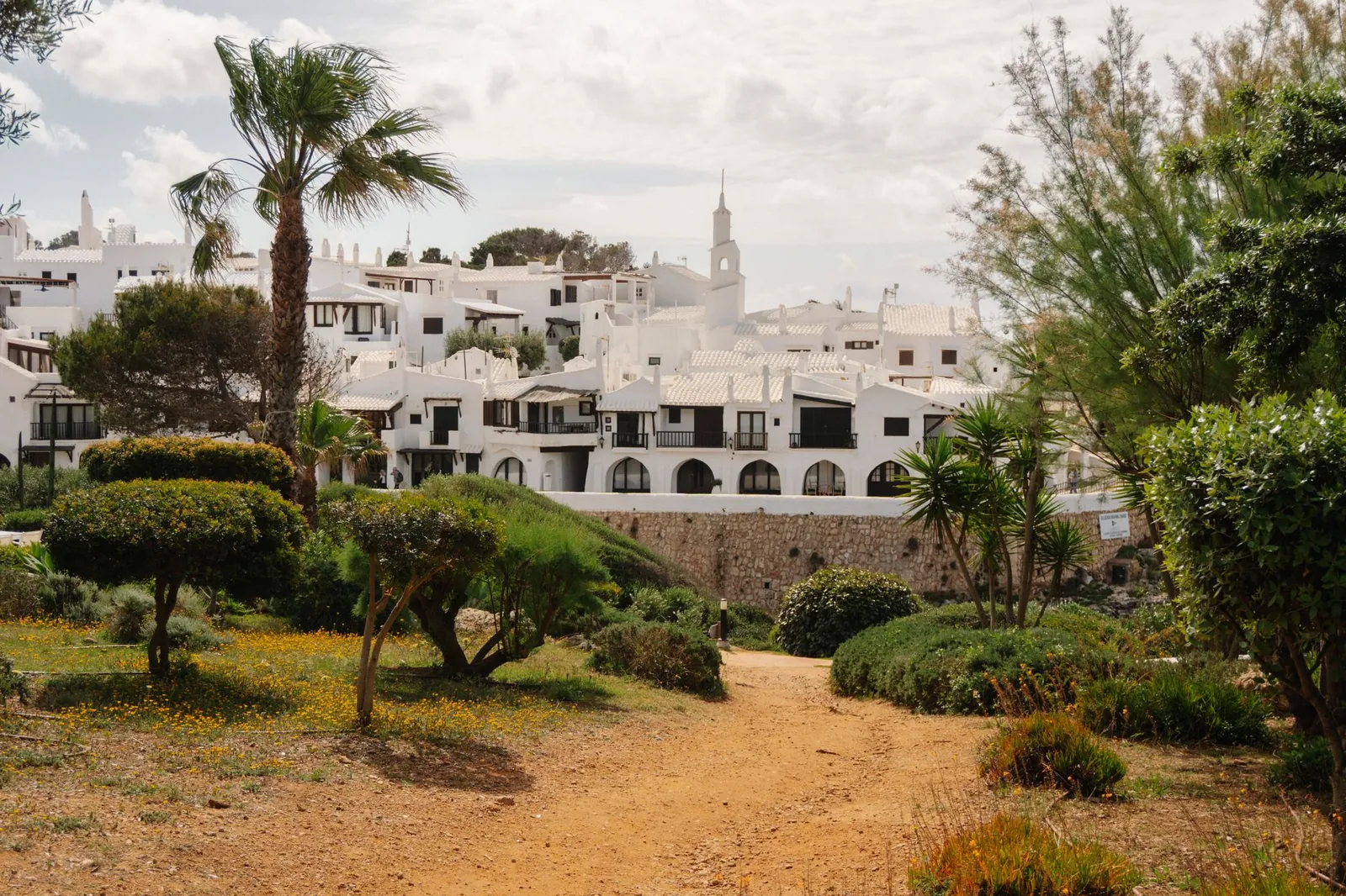 white architecture in Ciutadella de Menorca with greenery and palm trees in foreground