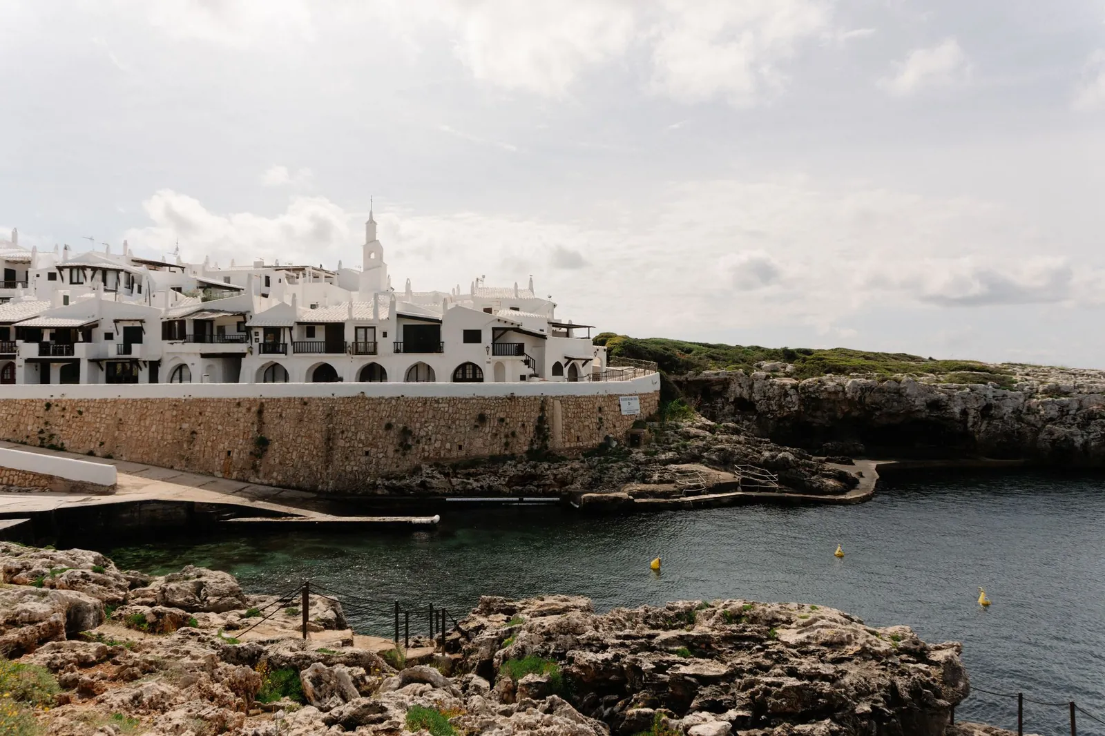 white buildings by rocky coast in Ciutadella de Menorca, Balearic Islands, Spain