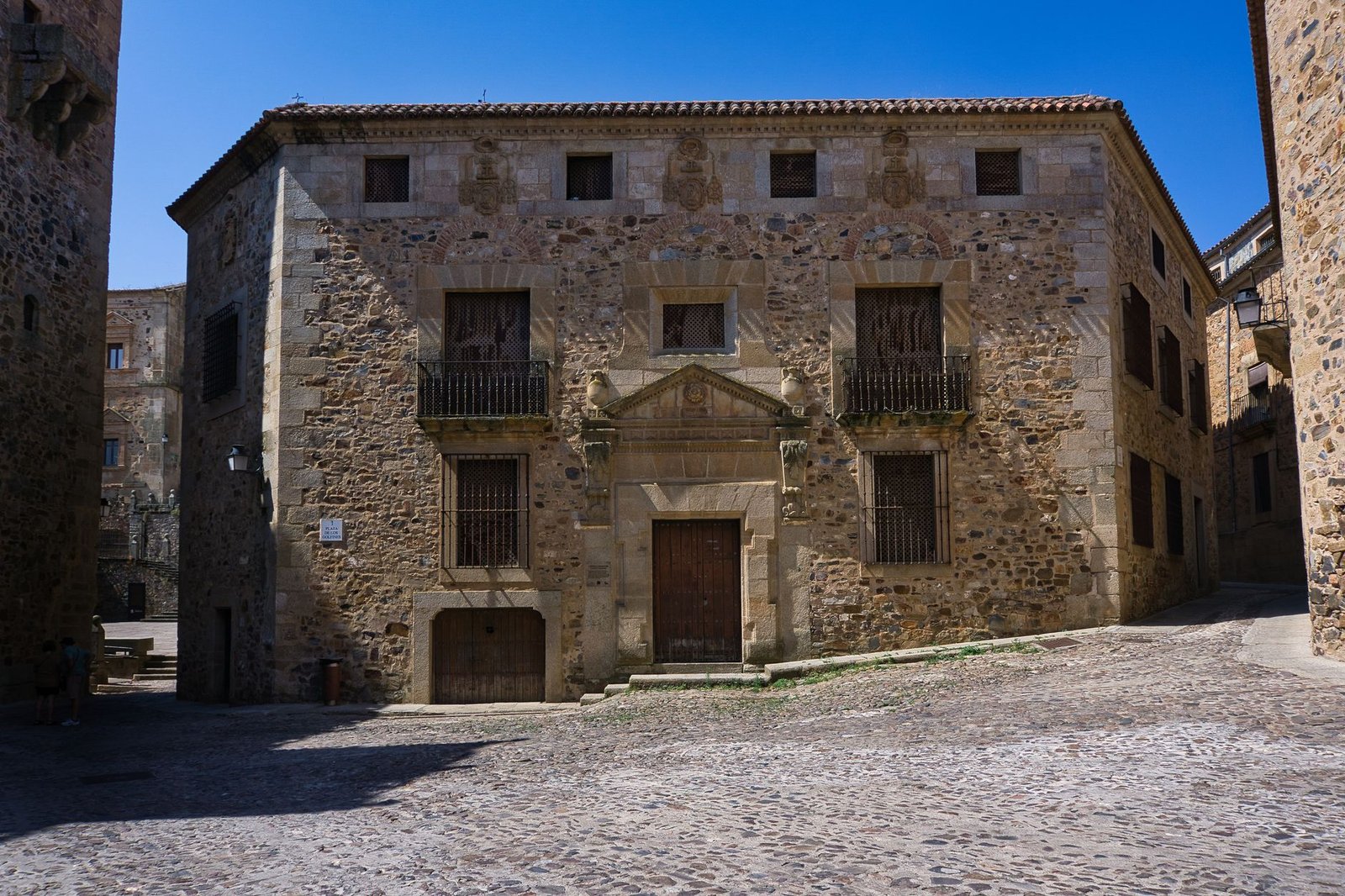 A centuries-old stone building in a sunlit historic town square