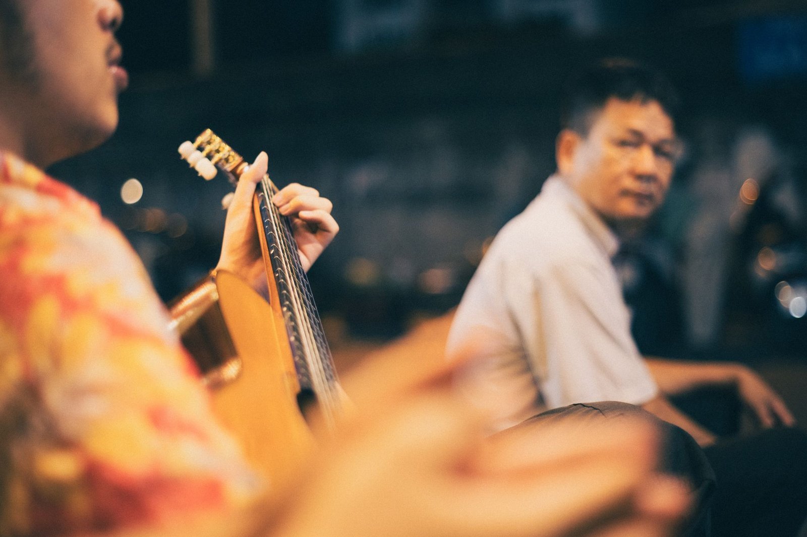 Musician playing guitar at night in Hanoi, capturing urban life in Vietnam