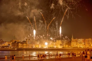 fireworks light up the night sky over a waterfront city, captivating an excited crowd below