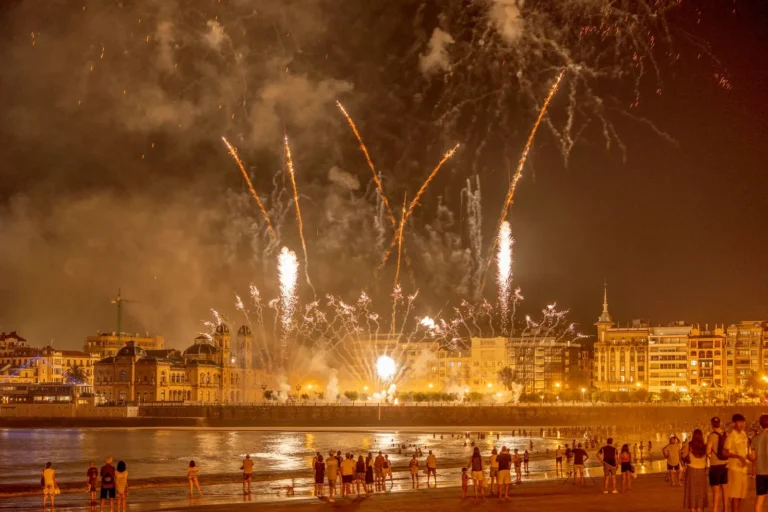 fireworks light up the night sky over a waterfront city, captivating an excited crowd below