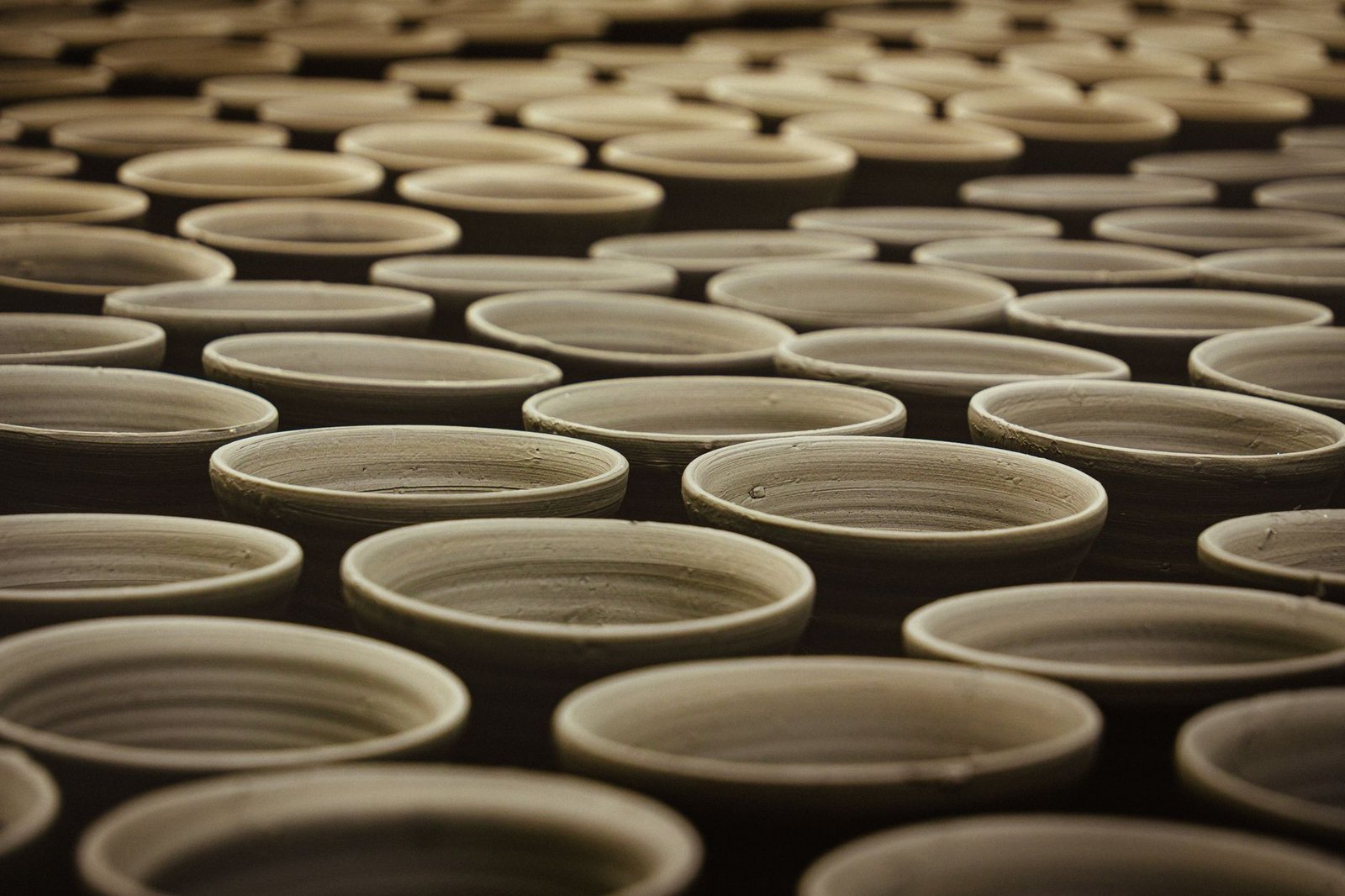 Multiple handcrafted clay pots aligned in a traditional pottery workshop
