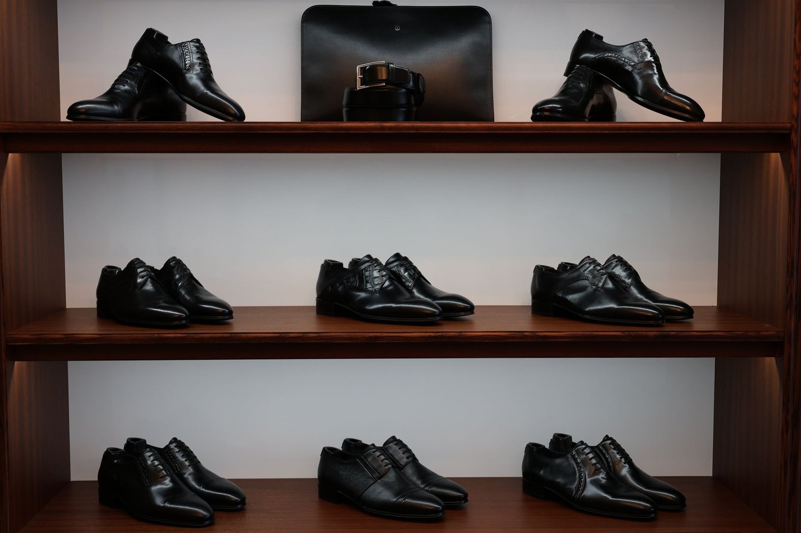 A stylish display of black leather shoes and accessories on wooden shelves in a store
