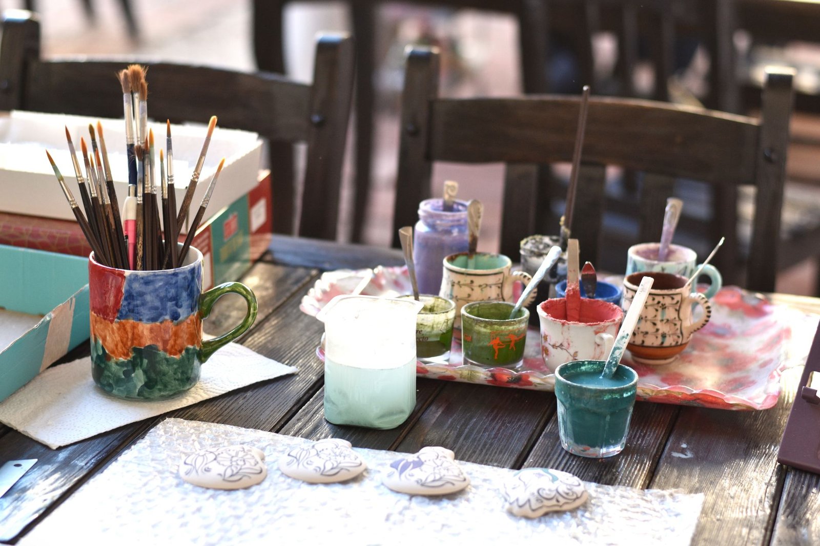 Creative ceramic art setup with paintbrushes and paints on a wooden table