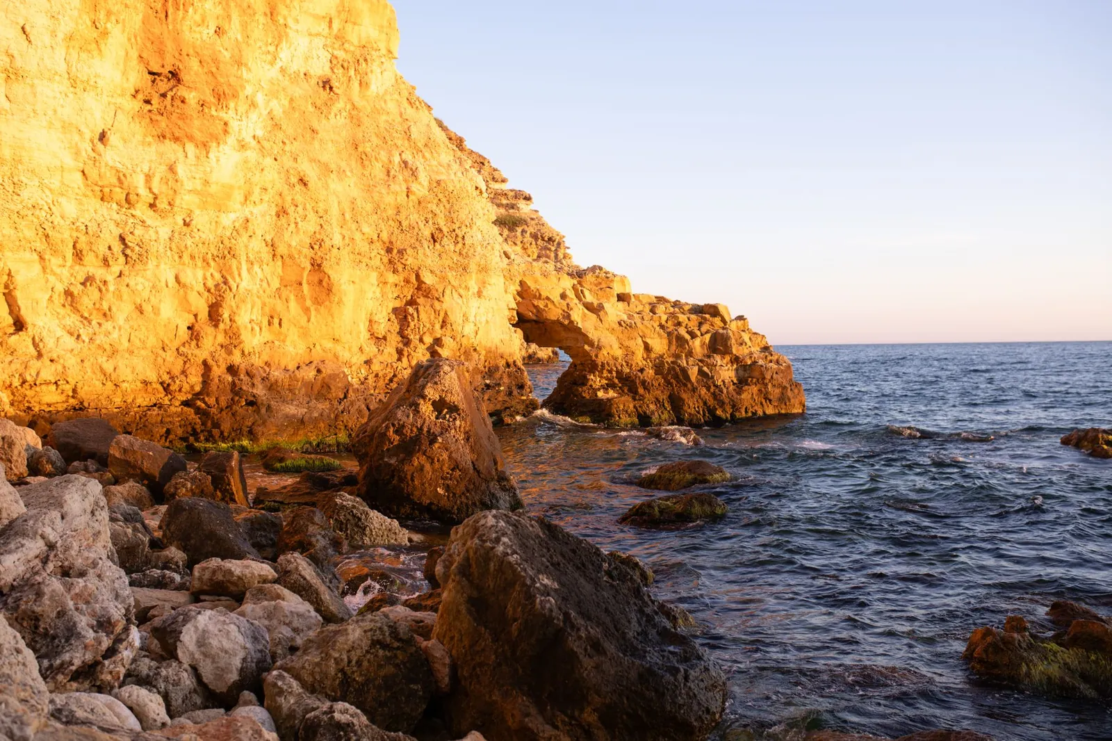 view of sunlit rocky cliffs and ocean waves in a scenic coastal landscape