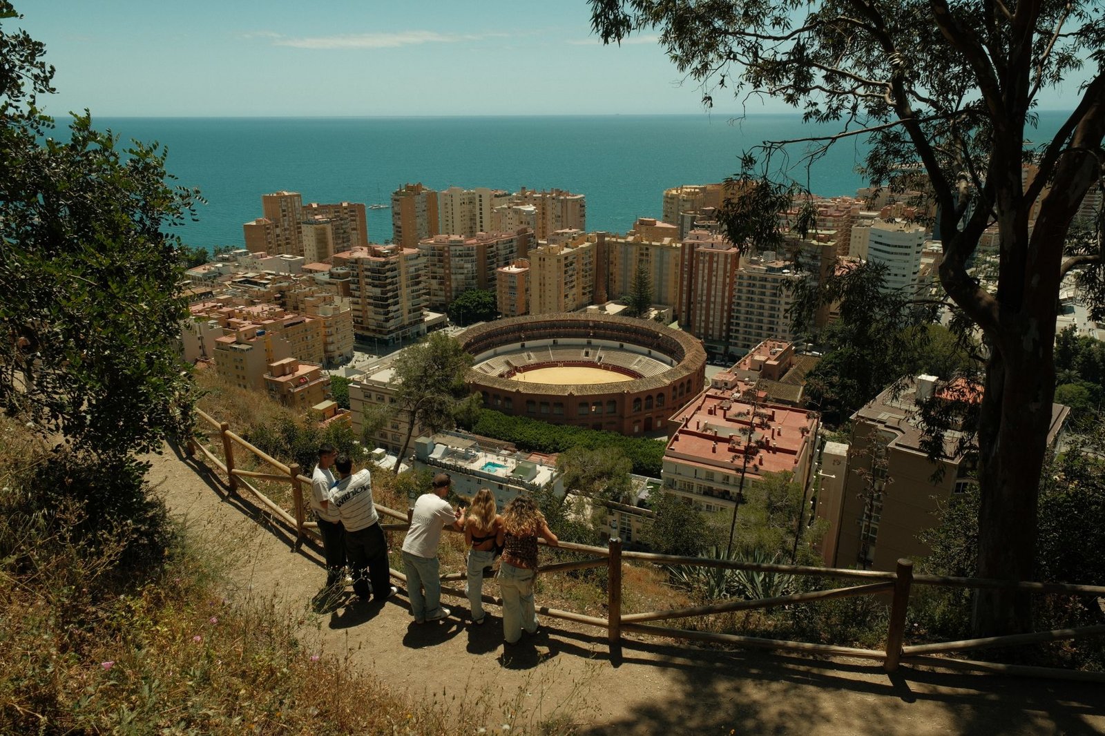 Aerial view of Malaga city skyline featuring the iconic bullring and Mediterranean Sea on a sunny day