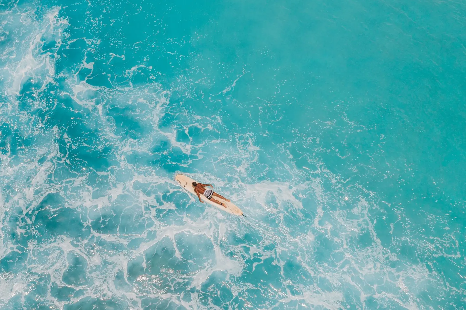 Aerial shot of a paddleboarder on the turquoise sea, capturing the essence of ocean relaxation