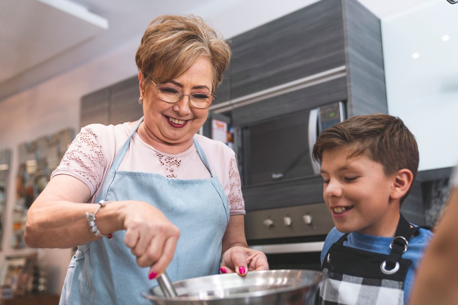 Senior woman and young boy enjoying cooking together in a modern kitchen setting