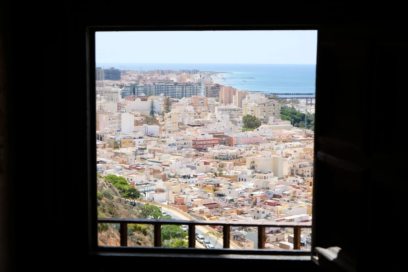 Aerial view of an urban coastal city through a window frame, showcasing buildings and the sea