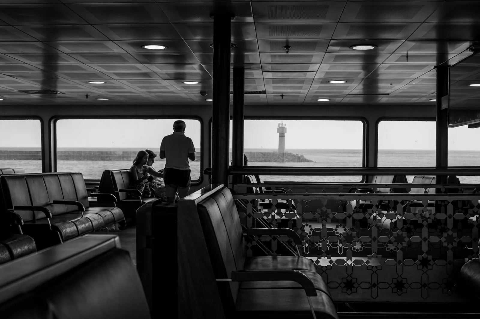 Black and white view inside an İstanbul ferry with a lighthouse visible through the window